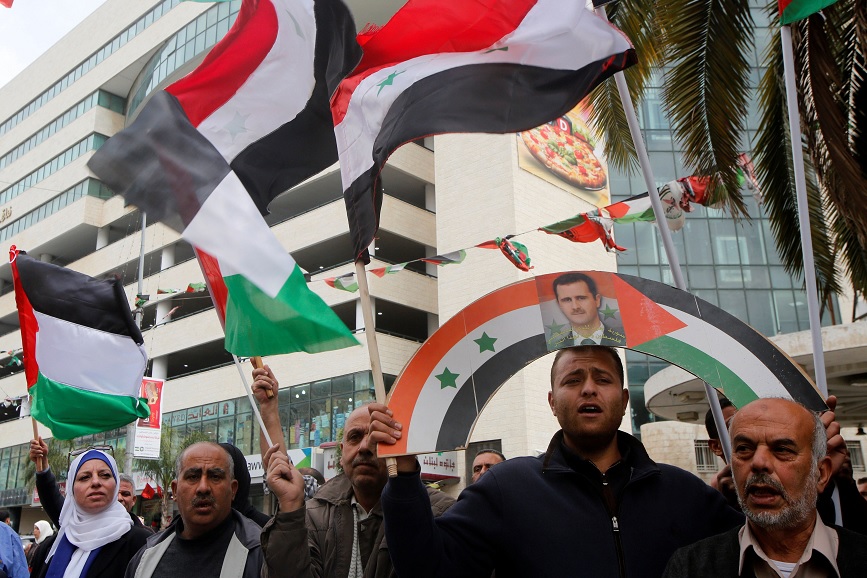Un grupo de palestinos tienen un cartel del presidente Bashar al-Assad, durante una protesta contra los ataques aéreos estadounidenses en Siria (Reuters)