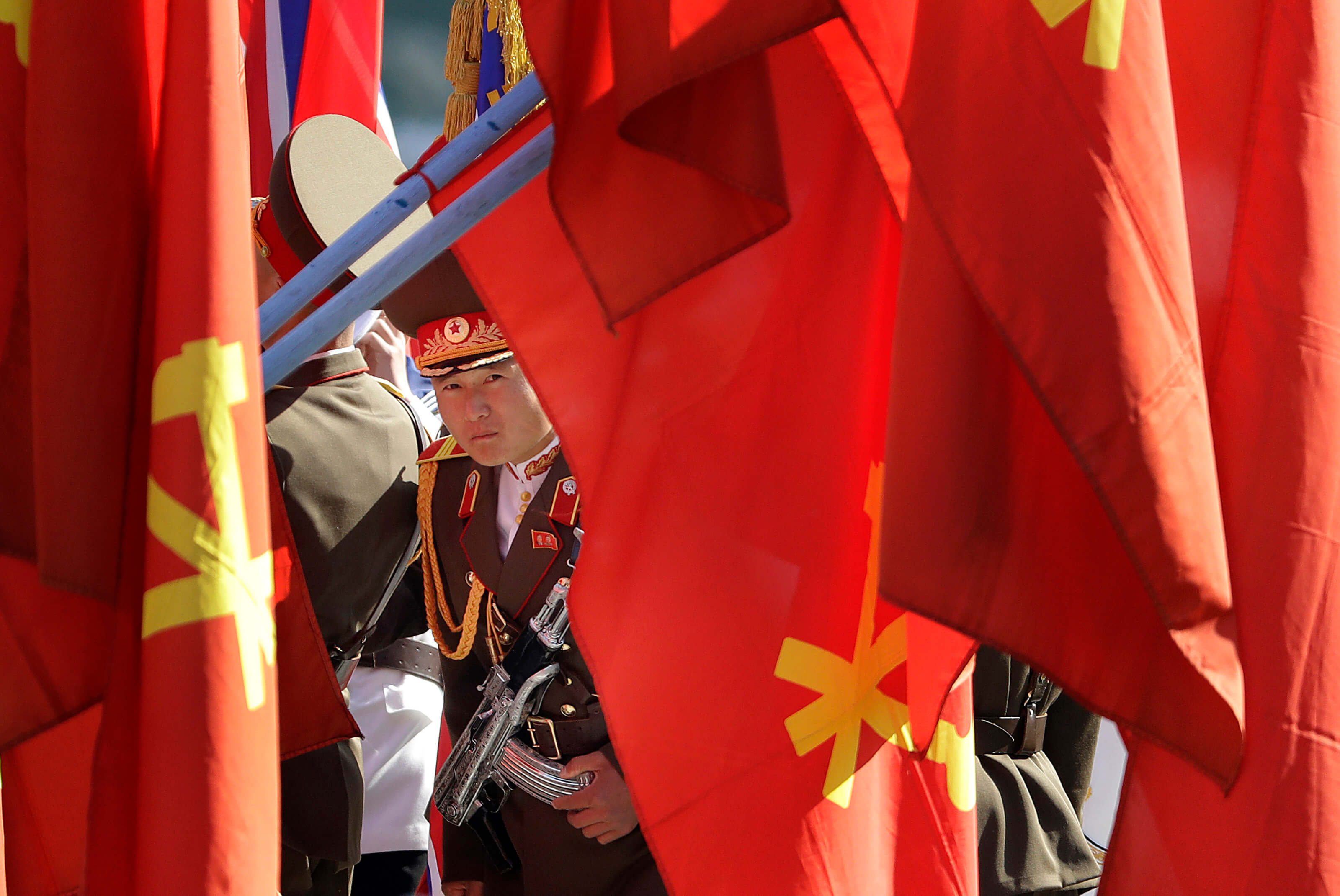 soldado norcoreano se asoma detras de varias banderas de su pais