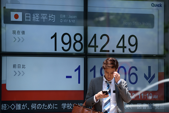 Peatón pasa frente a tablero electrónico de la Bolsa de Tokio