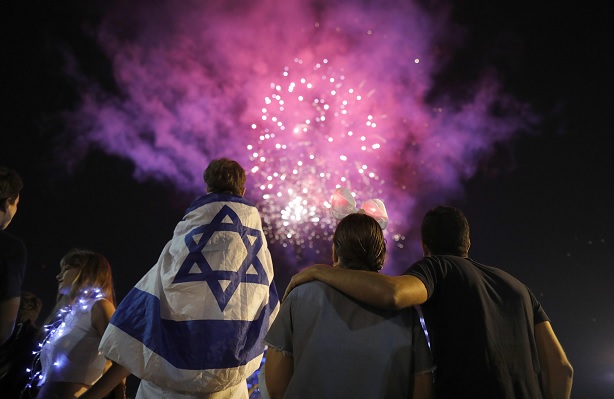 Israelíes sostienen banderas de su país mientras observan fuegos artificiales (EFE)