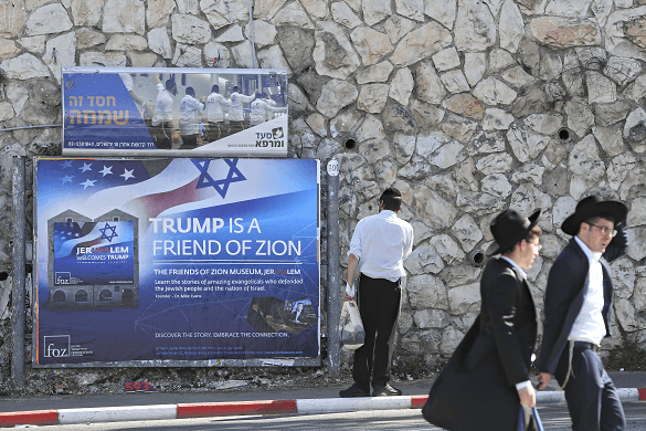 Judíos ultraortodoxos caminan frente a un cartel que da la bienvenida a Trump en Jerusalén