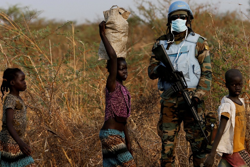 Un soldado de la ONU está de guardia mientras los niños caminan al norte de Sudán del Sur (Reuters)