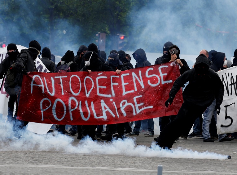Manifestantes enmascarados se protegen de gases lacrimógenos en París (Reuters)