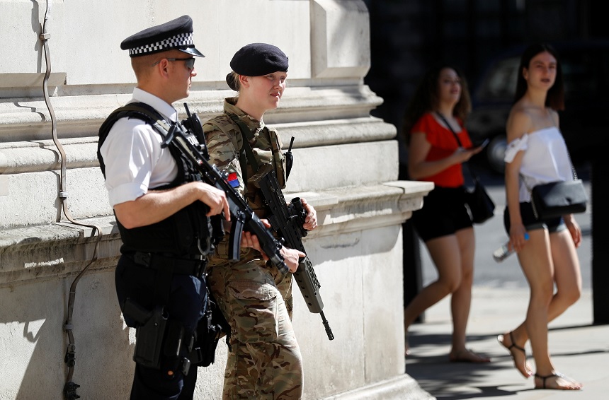 Los turistas pasan por delante de un soldado y un oficial de policía armado en Londres, Gran Bretaña (Reuters)
