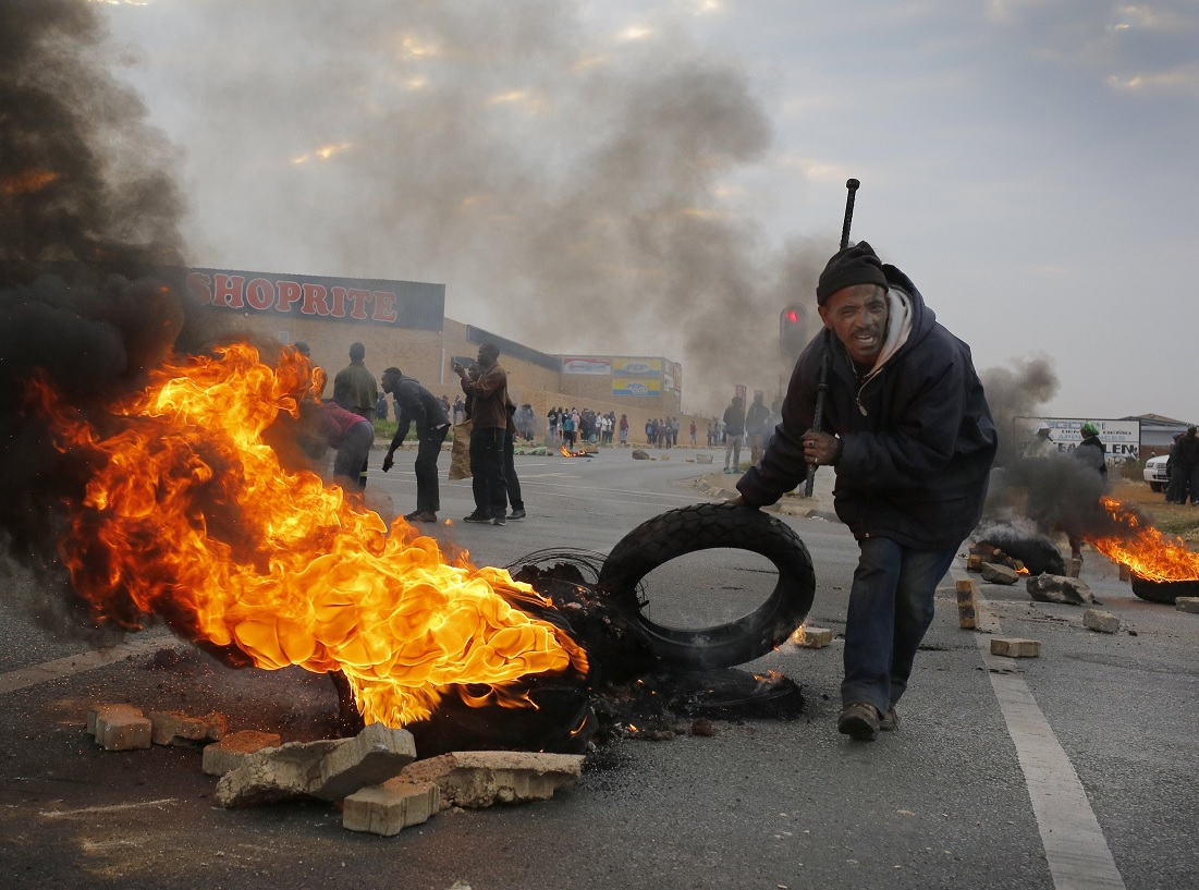 Un manifestante utiliza un neumático en llamas para construir una barricada durante una protesta en Johannesburgo, Sudáfrica (EFE)