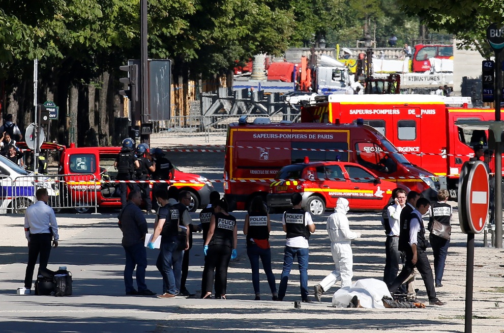 La policía inspecciona el cadáver de un hombre que impacto su automóvil con una camioneta de la gendarmería en la avenida de los Campos Elíseos en París (Reuters)