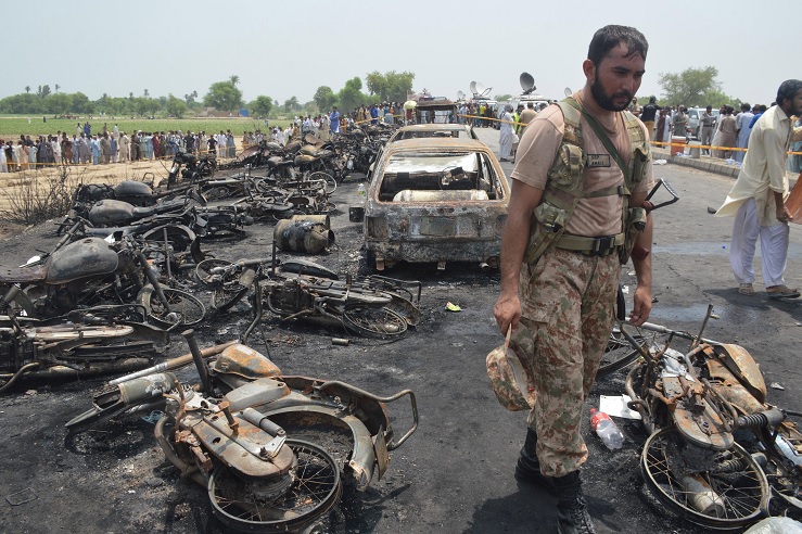 Un soldado pakistaní resguarda vehículos quemados en la escena de un accidente las afueras de Bahawalpur, Pakistán (EFE)