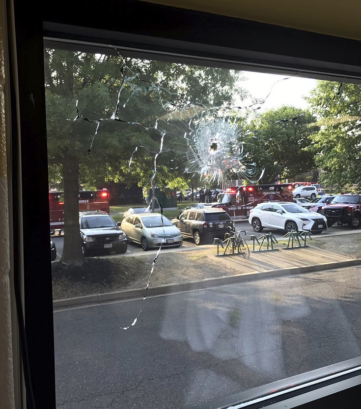 El personal de emergencia se ve a través de una ventana con un agujero de bala en Alexandria, Virginia (AP)