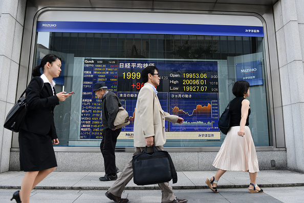Peatones frente a tablero de la Bolsa de Tokio