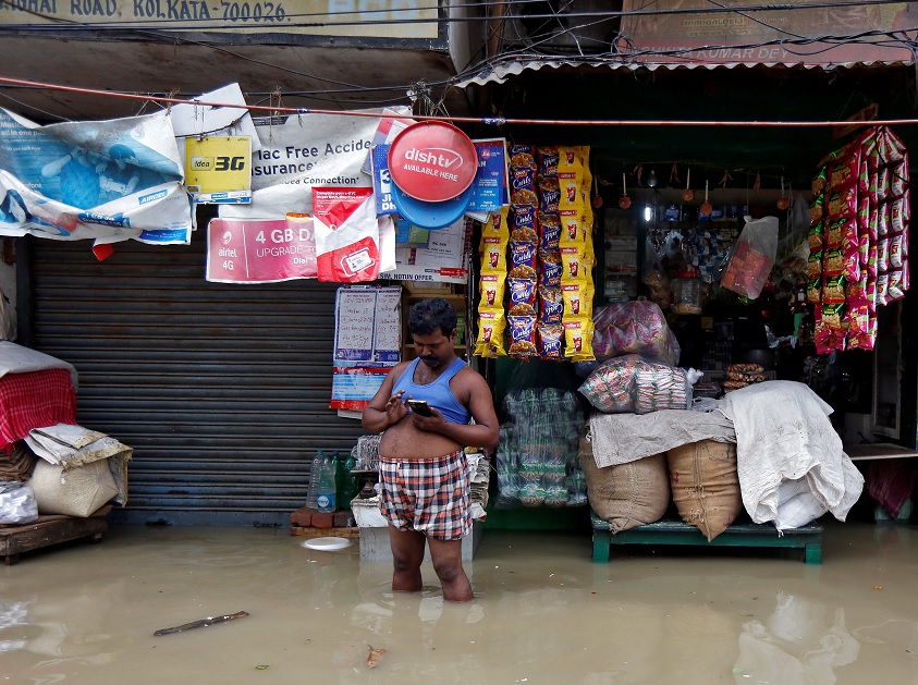 Hombre revisa telefono celular calle llena agua lluvia Kolkata India