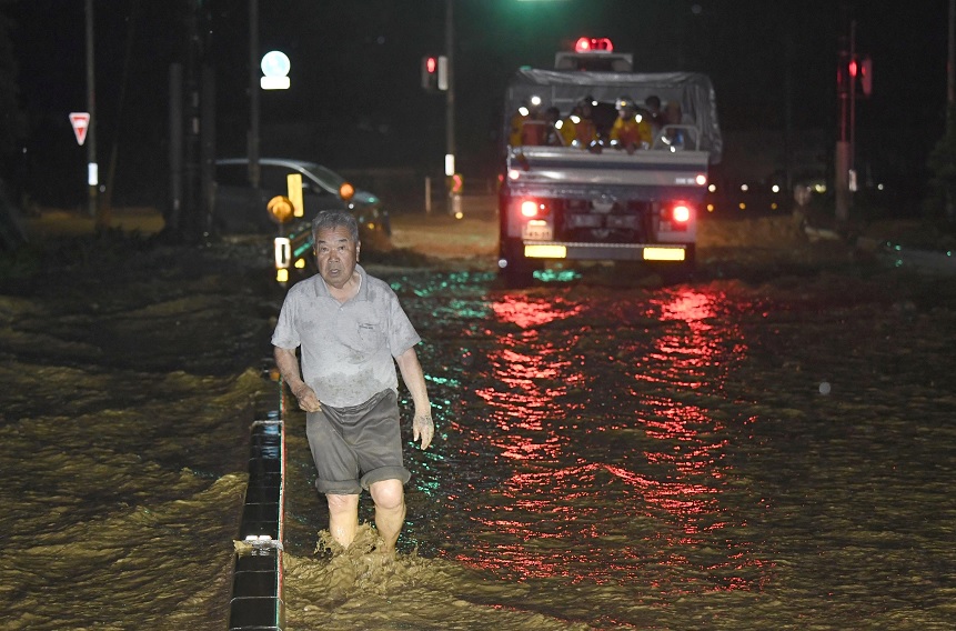 Un hombre camina a través de una calle inundada en Asakura, Japón (Reuters)