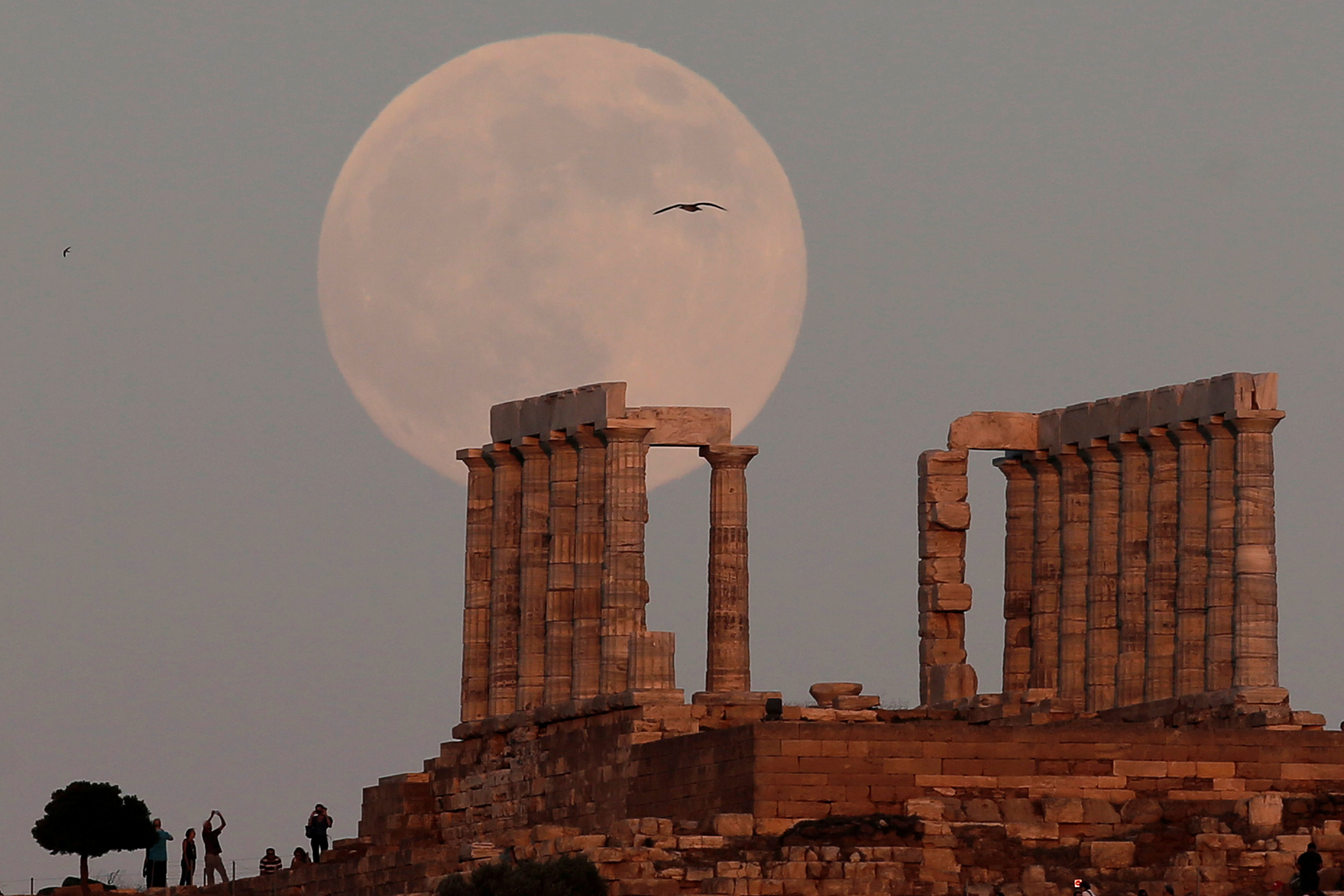 Luna llena se eleva sobre ruinas arqueológicas en Atenas