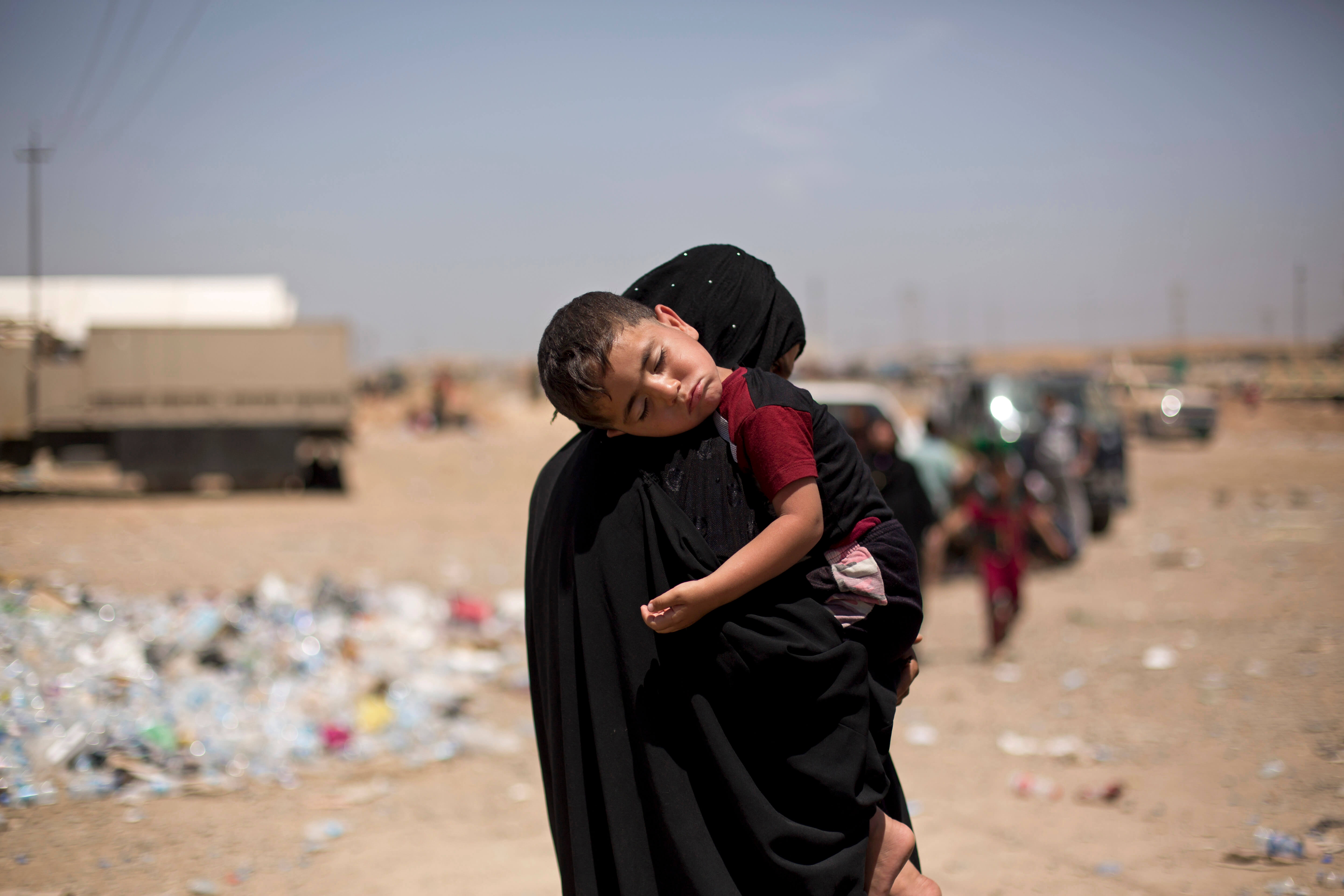 Mujer con hijab carga a nino dormido tras huir de Mosul