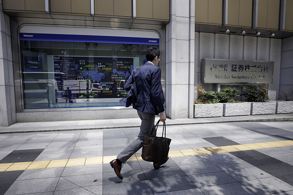 Peatón pasa junto a una firma de valores en Tokio