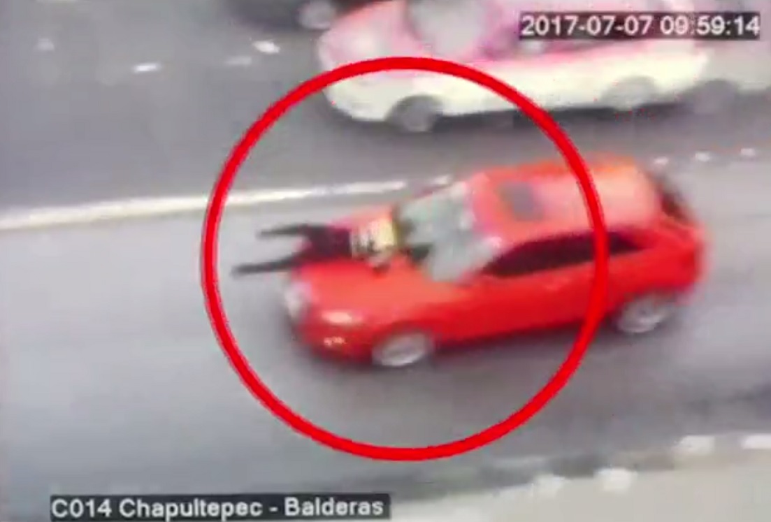 Policía se aferra al cofre de un vehículo. (Noticieros Televisa)