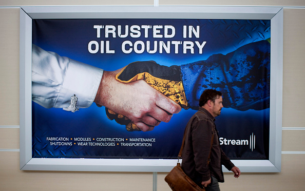 Hombre camina frente a un anuncio de petróleo canadiense