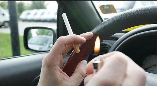 Una persona prende un cigarro dentro de su automóvil