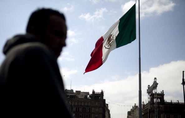 Hombre pasa junto a la bandera mexicana en el Zócalo