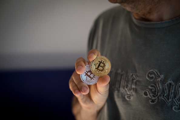Un hombre muestra dos criptomonedas denominadas Bitcoin