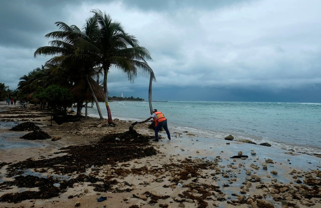 Un trabajador limpia la playa tras el paso de Franklin. (Reuters)