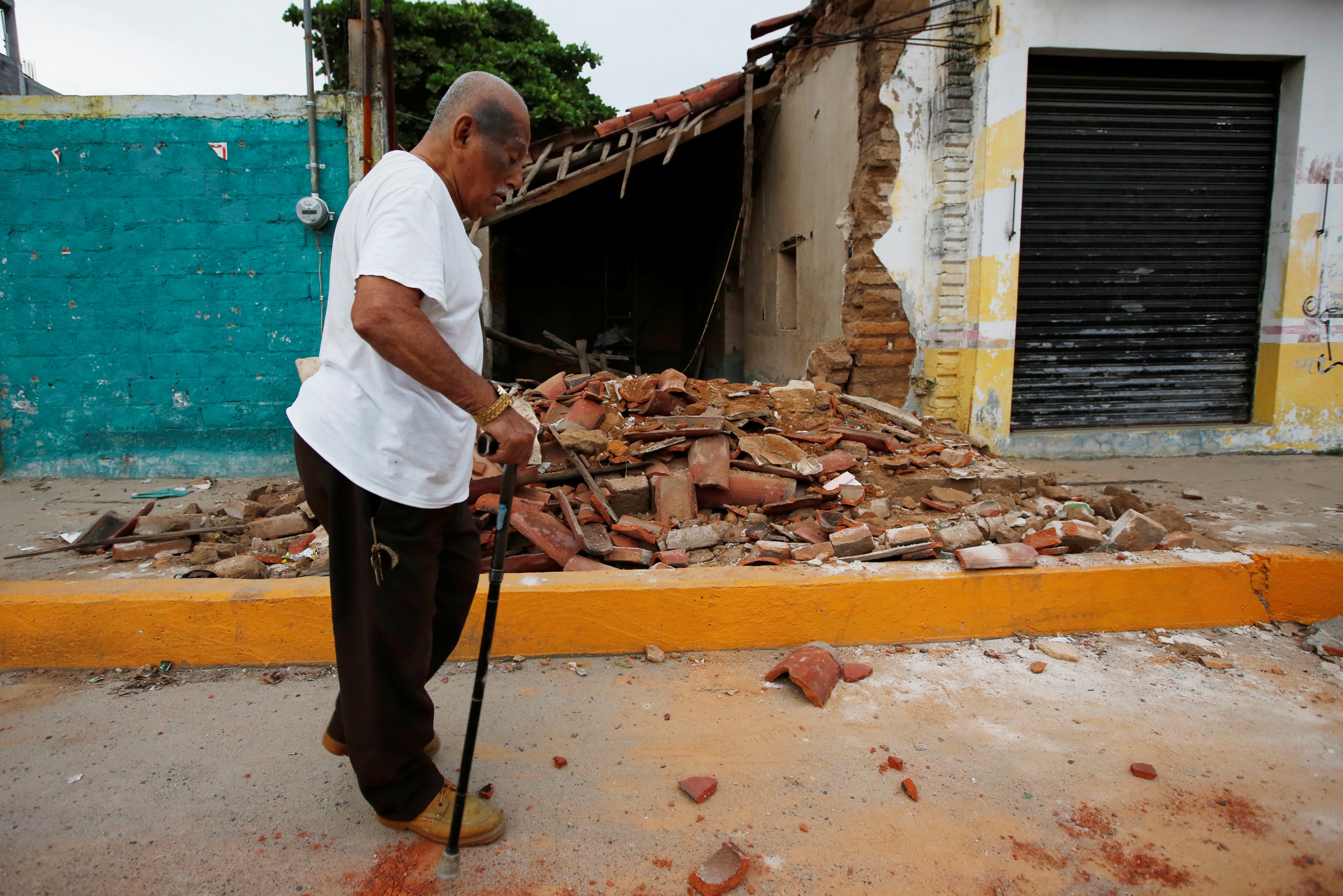 Hombre camina frente a una vivienda destruida por el sismo