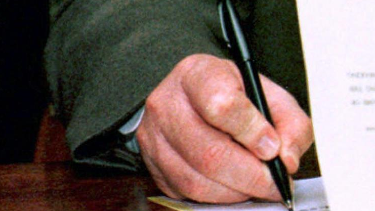 Un hombre firma un documento Ap