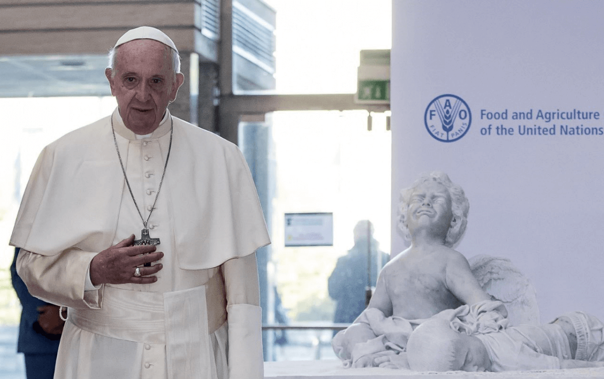 El papa posa junto a una escultura de mármol que muestra el drama de la migración