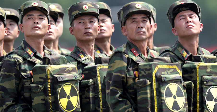 Soldados norcoreanos cargan paquetes con el símbolo nuclear durante desfile oficial