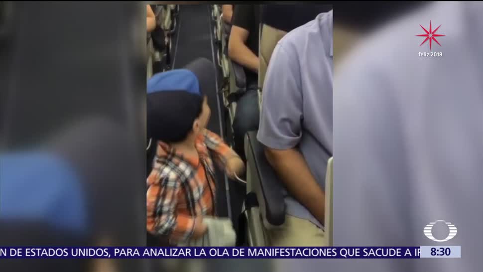 Niño saluda a cada pasajero en el pasillo de un avión