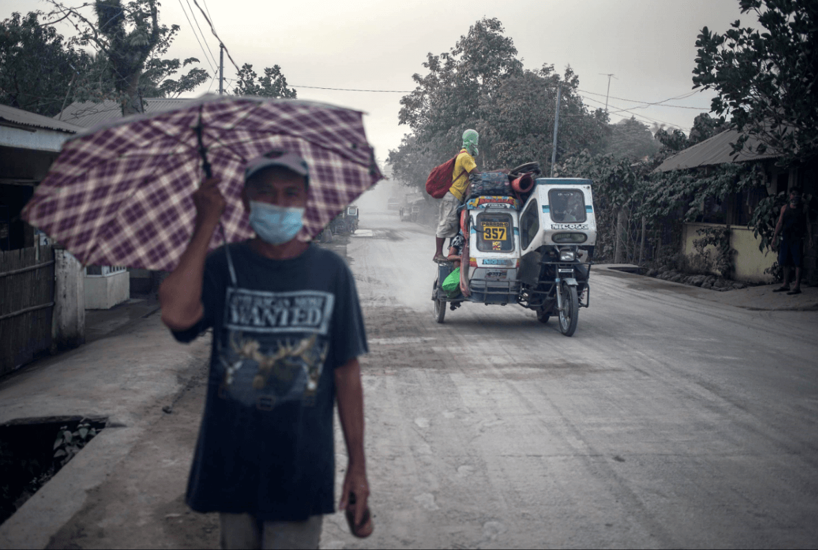 Las personas se protegen tras la caída de cenizas en Filipinas. (EFE) 