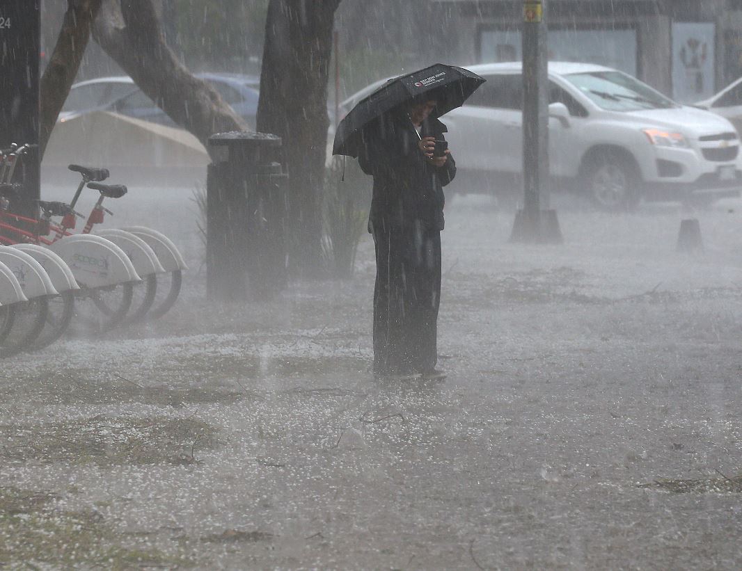 foto:Una persona se protege de la fuerte lluvia, 6 julio 2019