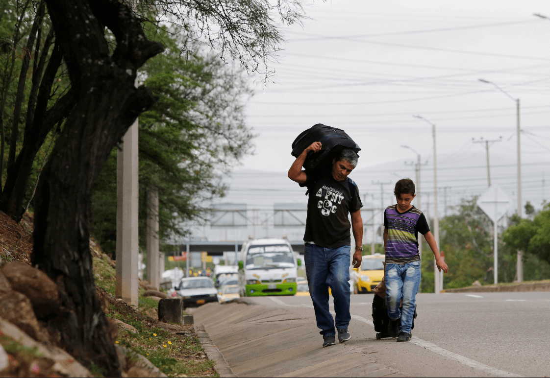 Un padre venezolano y su hijo buscan ingresar en Colombia. (AP) 
