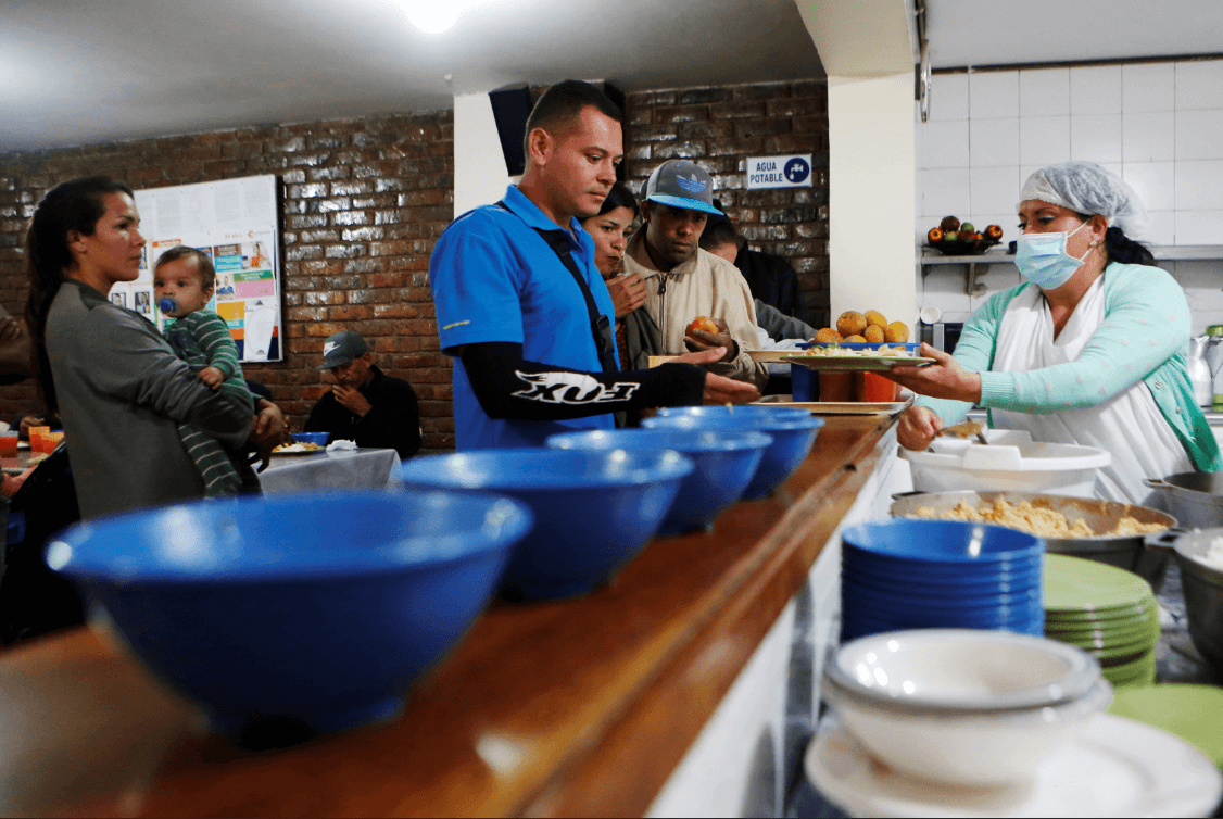 Migrantes venezolanos reciben alimentos en la arquidiócesis de Bogotá. (Reuters) 