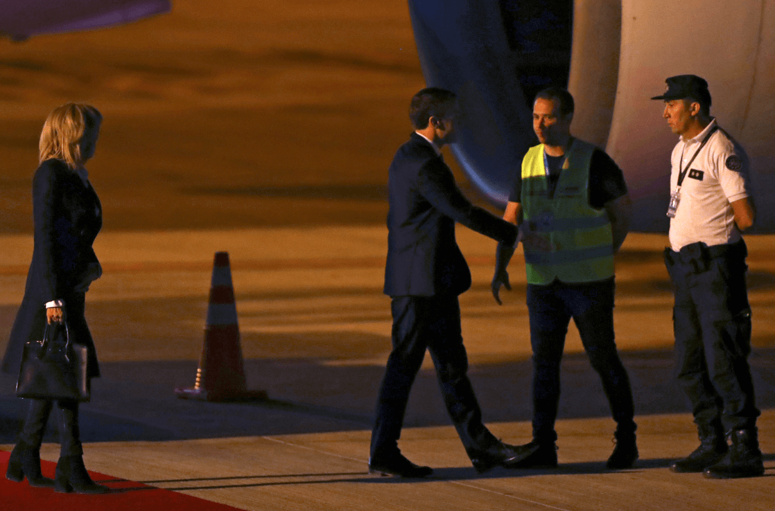 Empleados del aeropuerto reciben a Macron, ante el retardo de la vicepresidenta. (Reuters) 