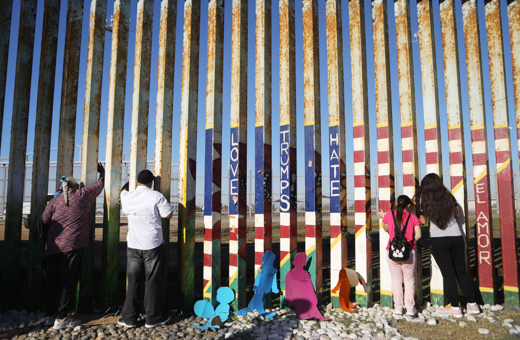 Foto: Una familia migrante protesta en la valla fronteriza entre San Diego y Tijuana