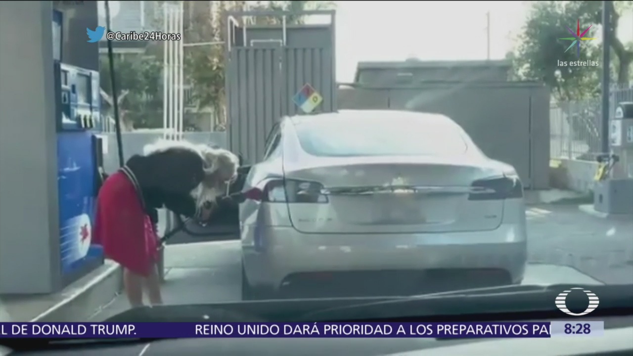 Mujer intenta poner combustible a un carro eléctrico