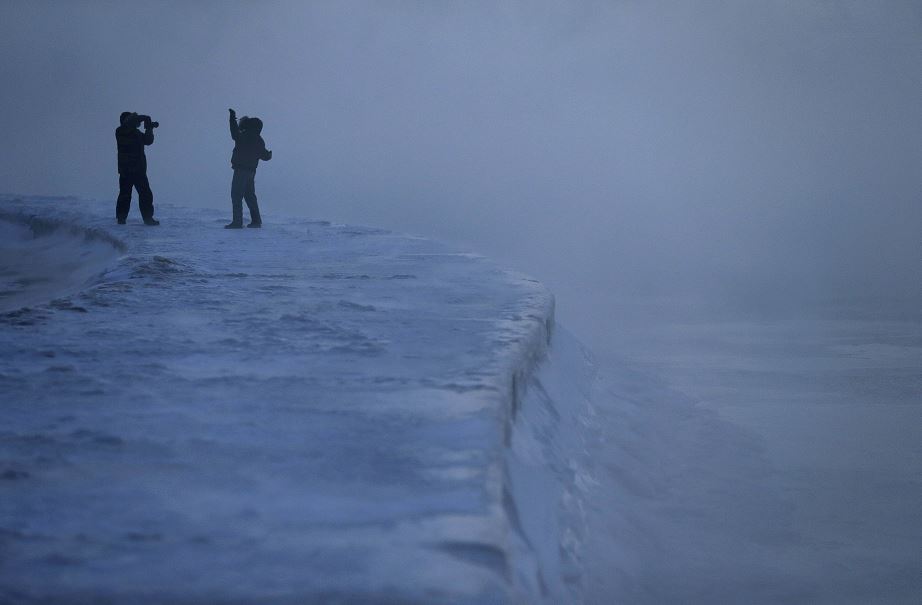 Foto: Un hombre posa para una foto mientras el hielo se forma a lo largo de la orilla del lago Michigan