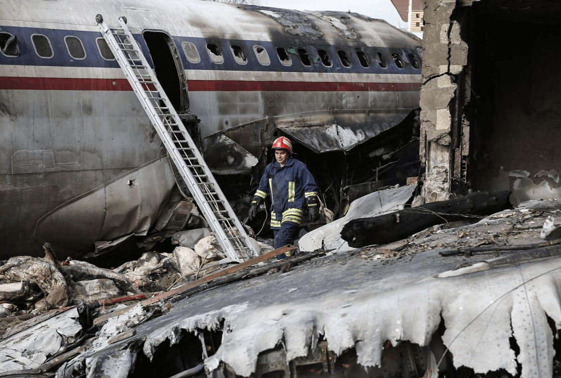 Un hombre camina entre los restos del fuselaje de un avión accidentado en Irán. (EFE) 