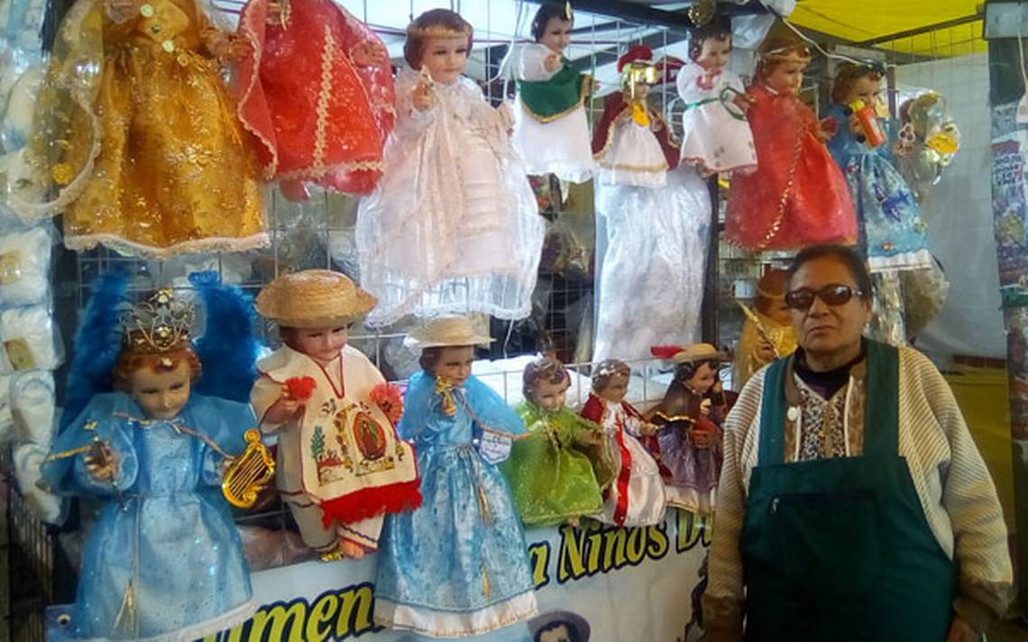 Una vendedora junto a su puesto de niños Jesús vestidos para el Día de la Candelaria (Puebla Hoy)