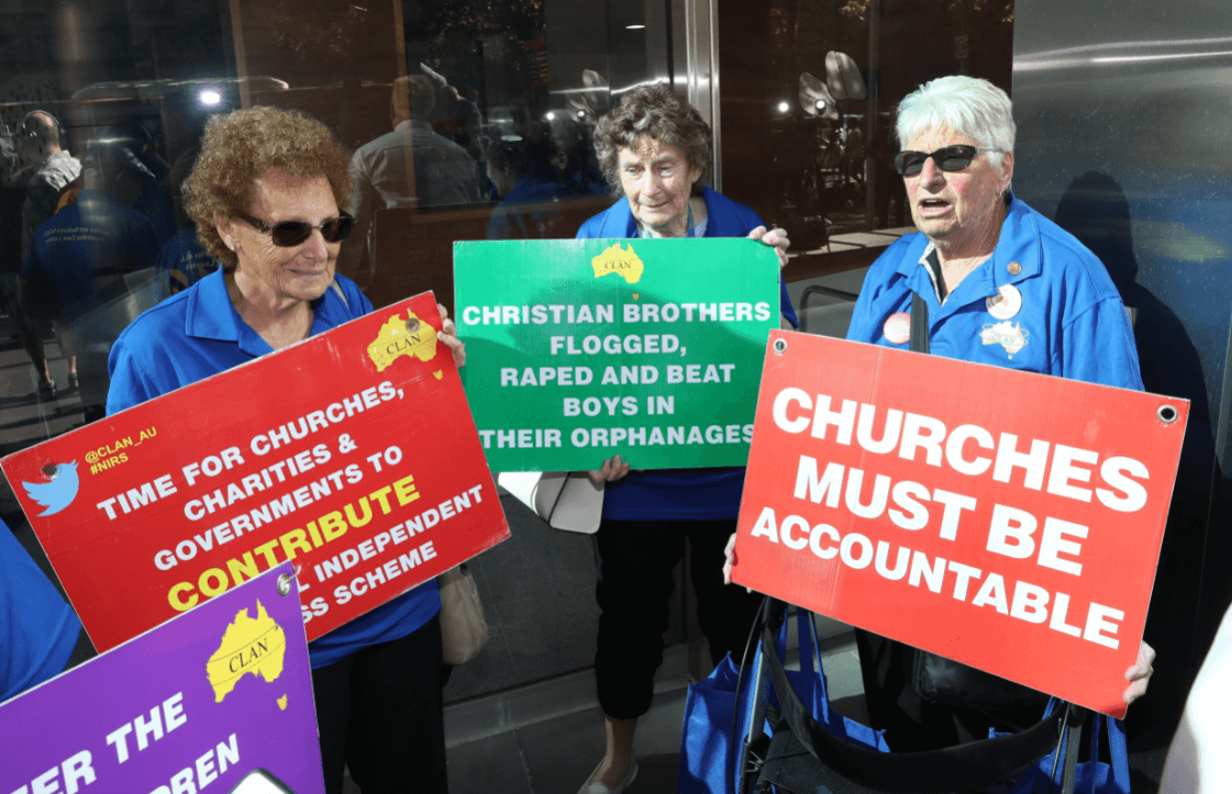 Foto: Mujeres sostienen carteles en contra de los abusos sexuales cometidos por sacerdotes, 27 de febrero 2019, Melbourne, Australia