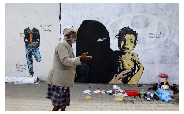 Un hombre en Yemen camina frente a un grafiti, 21 de febrero de 2019, Sana, Yemen