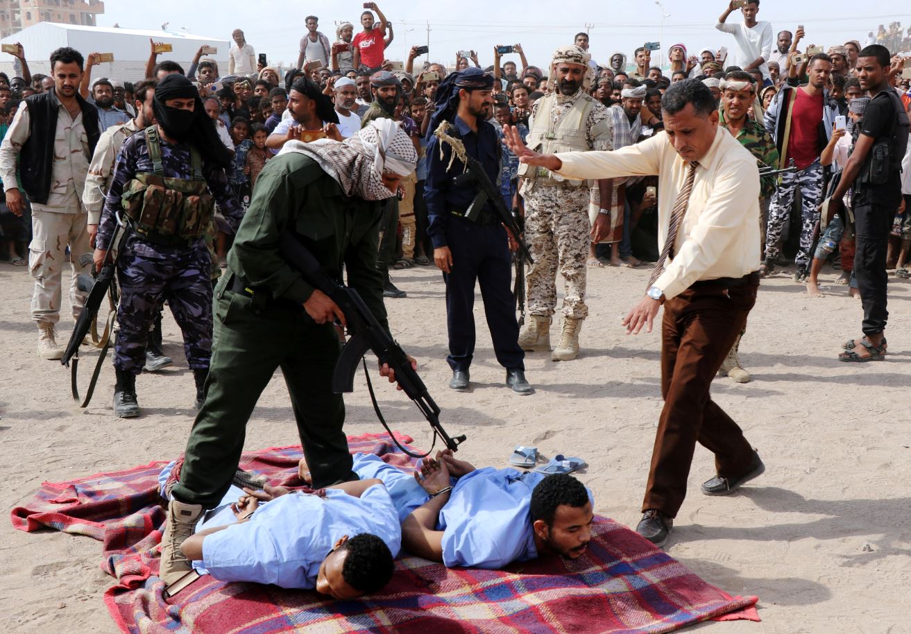 Un militar apunta un arma larga contra las espaldas de Refat y Khaled, sentenciados a muerte por secuestro, violación y asesinato de un menor de edad (Reuters)