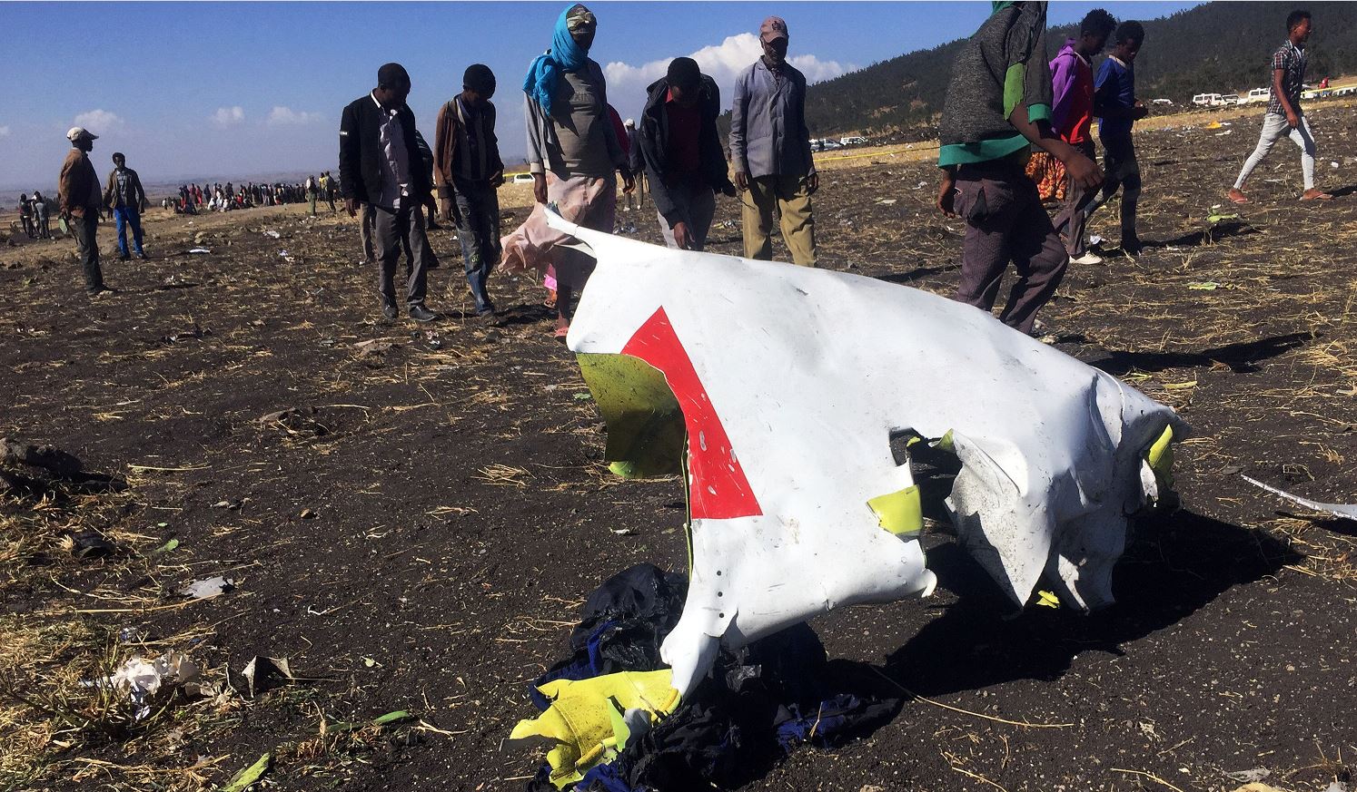 Foto: La gente pasa frente a una parte de los escombros en la escena del accidente aéreo de Ethiopian Airlines, 10 marzo 2019