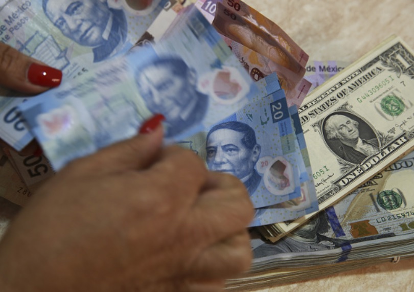 Foto: Un trabajador cuenta los billetes en pesos mexicanos además de los billetes en dólares estadounidenses en una tienda de cambio en Ciudad de México, marzo 11 de 2019 (Getty Images)