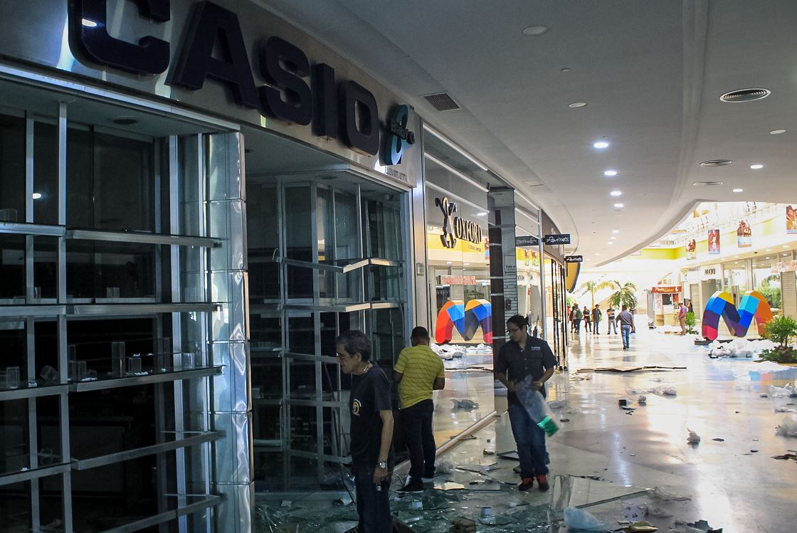 Varias personas observan los daños en locales del centro comercial Sambil en Maracaibo, Venezuela, 14 marzo 2019