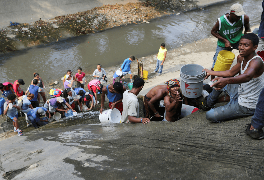 Venezolanos recogen agua en río contaminado debido a apagón