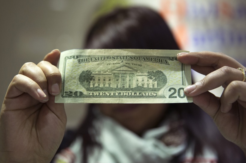 Foto: Un trabajador inspecciona un billete de veinte dólares de Estados Unidos en el Aeropuerto Internacional Benito Juárez en la Ciudad de México, abril 9 de 2019 (Getty Images)