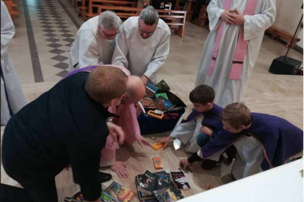 Los sacerdotes apilan libros y objetos de la franquicia al pie de un altar de iglesia (Facebook/smsznieba)