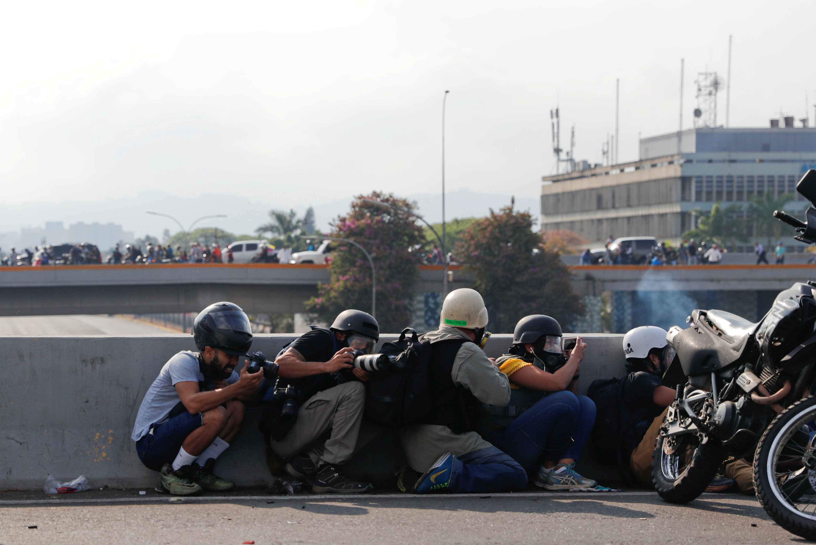 Periodistas y miembros de los medios de comunicación toman resguardo frente a la base militar 'La Carlota' (Reuters)