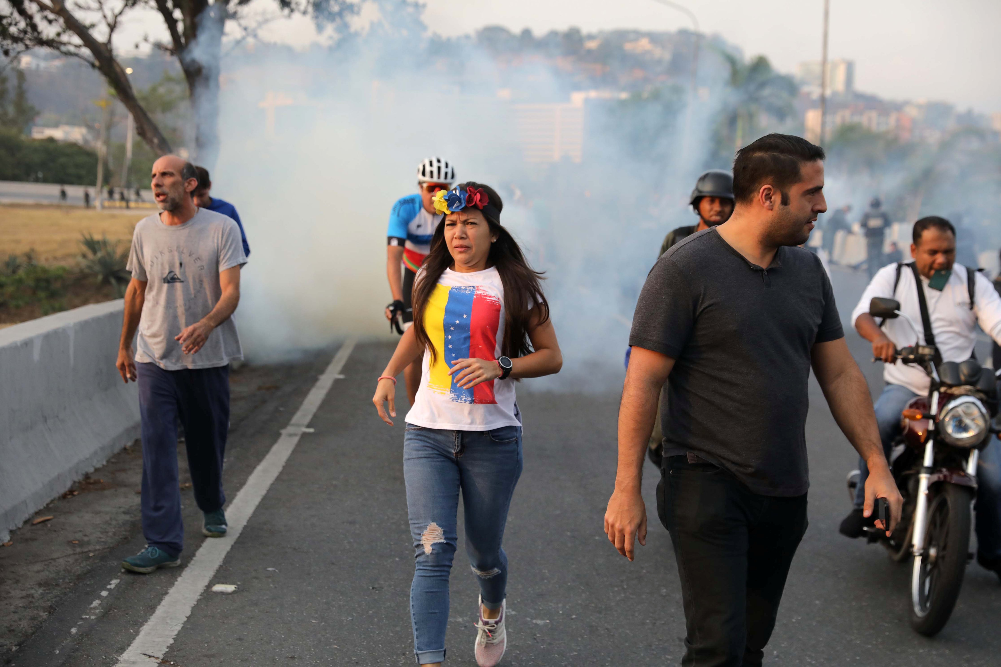 Pobladores de Caracas que salieron a las calles ante el llamado de Guaidó huye de los gases lacrimógenos (Reuters)